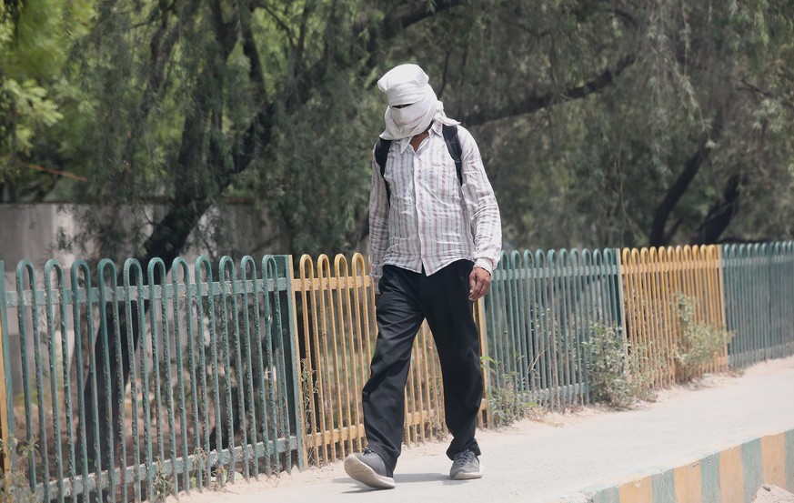 epa09920061 A man walks with his head covered against the sun during a hot afternoon on the outskirts of New Delhi, India, 01 May 2022. According to the India Meteorological Department (IMD), Delhi an ...