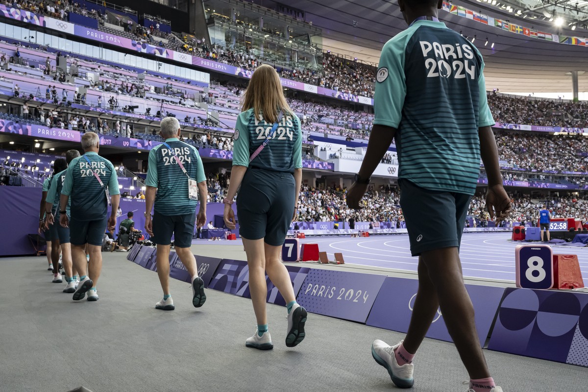 Volunteers walk along the athletics track at the Stade de France, at the 2024 Paris Summer Olympics in Paris, France, Sunday, August 4, 2024. (KEYSTONE/Anthony Anex)