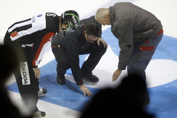 Geneve-Servette&#039;s Head coach Chris McSorley, center, between Head referee Stefan Eichmann, left, and a technician, right, looks on a hole into the ice, during the Swiss Ice Hockey Cup round of 16 ...