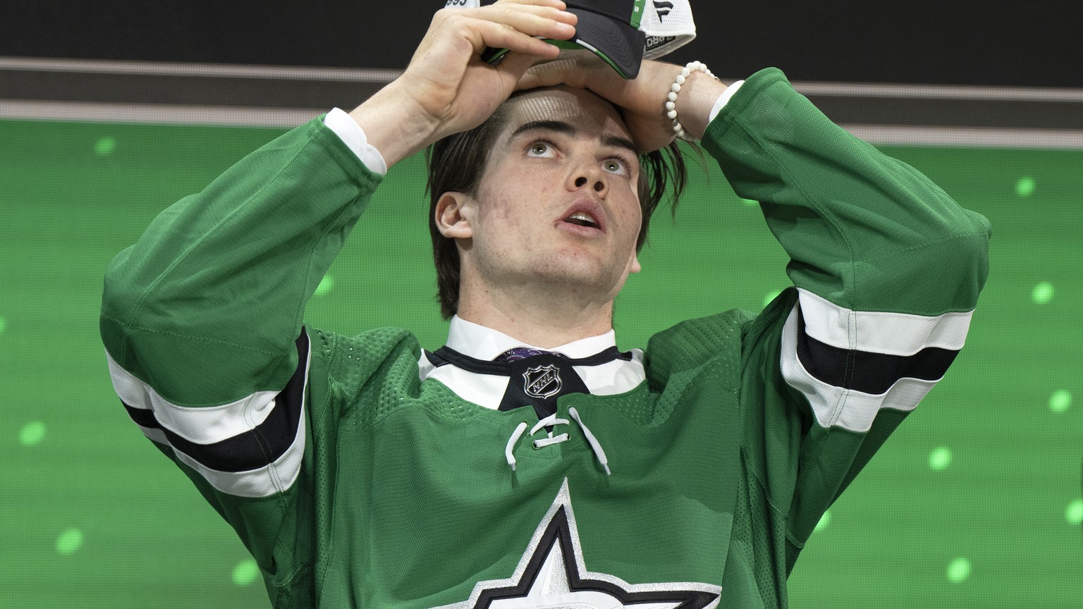 The Dallas Stars&#039; 18th pick, Lian Bichsel, puts on his cap during the first round of the NHL hockey draft Thursday, July 7, 2022, in Montreal. (Ryan Remiorz/The Canadian Press via AP)