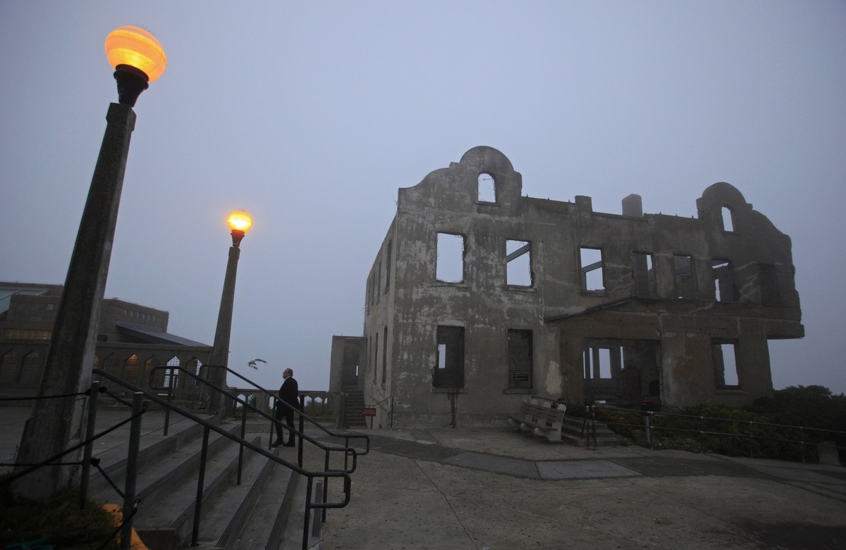 In this photo taken Thursday July 7, 2011, a man walks past the remains of the warden's house during a night tour on Alcatraz Island in San Francisco. Most of the more than one million tourists w ...