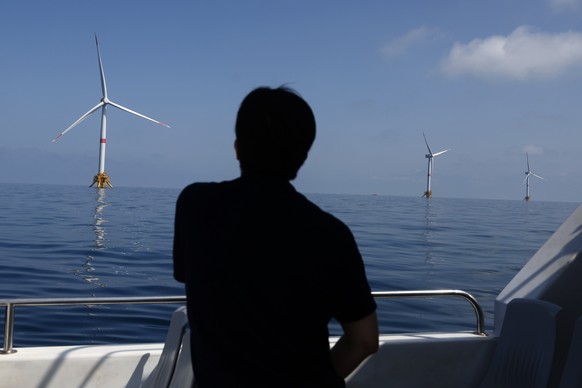 epaselect epa12192953 A journalist looks at three floating offshore wind turbines at the Provence Grand Large project in the Gulf of Fos-sur-Mer, France, 23 June 2025. The project is part of a large o ...