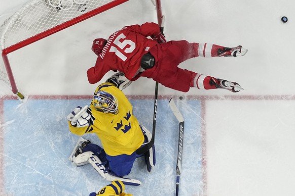 Russian Olympic Committee's Pavel Karnaukhov (15) collides with Sweden goalkeeper Lars Johansson during overtime in a men's semifinal hockey game at the 2022 Winter Olympics, Friday, Feb. 18, 2022, in Beijing. (AP Photo/Matt Slocum)