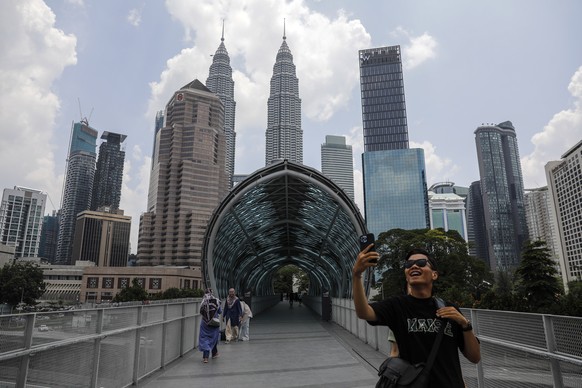 epa10914340 A man takes a selfie with the skyline of the capital city of Kuala Lumpur, Malaysia, 12 October 2023. &#039;Goldman Sachs&#039; arbitration against the government is premature and lacking  ...