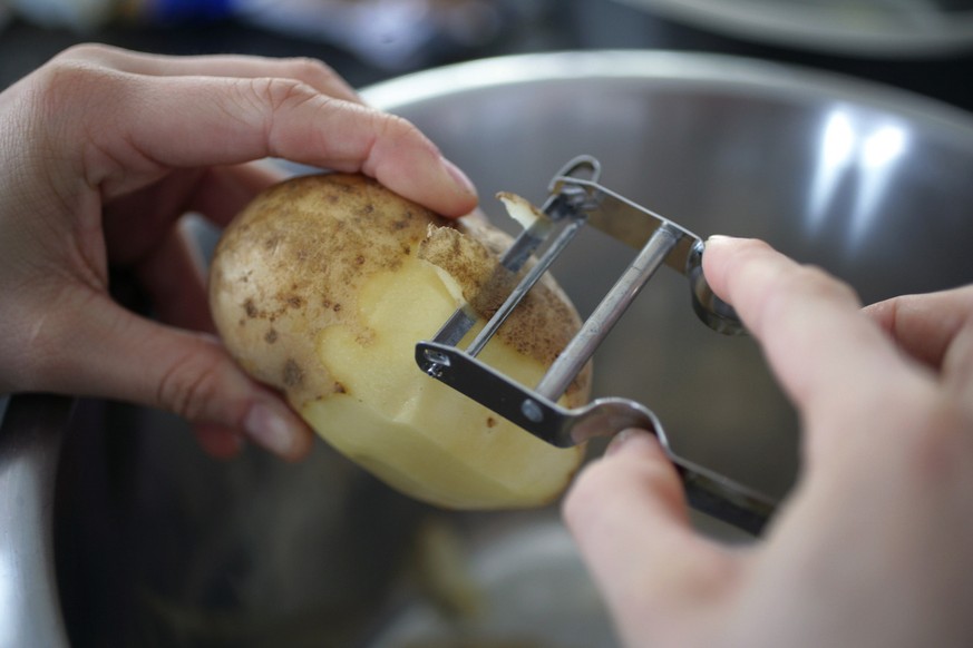 Eine Kartoffel wird im Februar 2005 mit einem Sparschaeler REX geschaelt. (KEYSTONE/Martin Ruetschi)