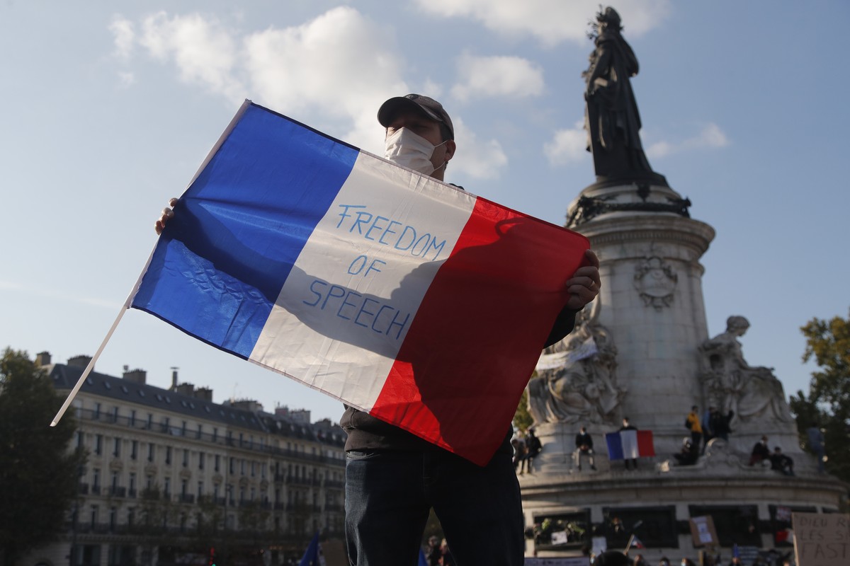 A demonstrator holds a French flag with the slogan "Freedom of Speech" during a demonstration Sunday Oct. 18, 2020 in Paris. Demonstrations around France have been called in support of freed ...