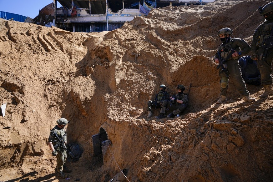 Israeli soldiers guard a crater-like hole giving way to a small tunnel entrance in the UNRWA compound where the military discovered tunnels underneath the main headquarters of the U.N. agency that the ...
