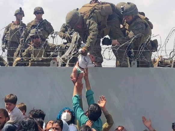In this image from video provided by Omar Haidari and taken on Thursday, Aug. 19, 2021 which shows a baby being lifted across a wall at Kabul Airport in Afghanistan by US soldiers. The image grabbed f ...