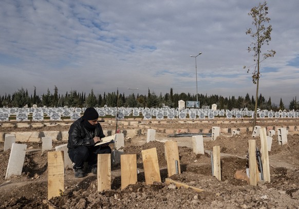 epa10476670 A man reads Koran at the graves of his relatives after powerful earthquake in Adiyaman, Turkey, 19 February 2023. More than 45,000 people have died and thousands more are injured after two ...