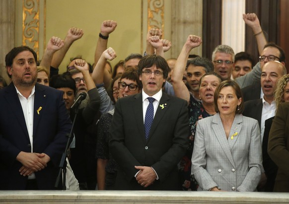 Catalan President Carles Puigdemont, center, Vice President Oriol Junqueras, left, and Carme Forcadell, the parliament president, sing the Catalan anthem inside the parliament after a vote on independ ...