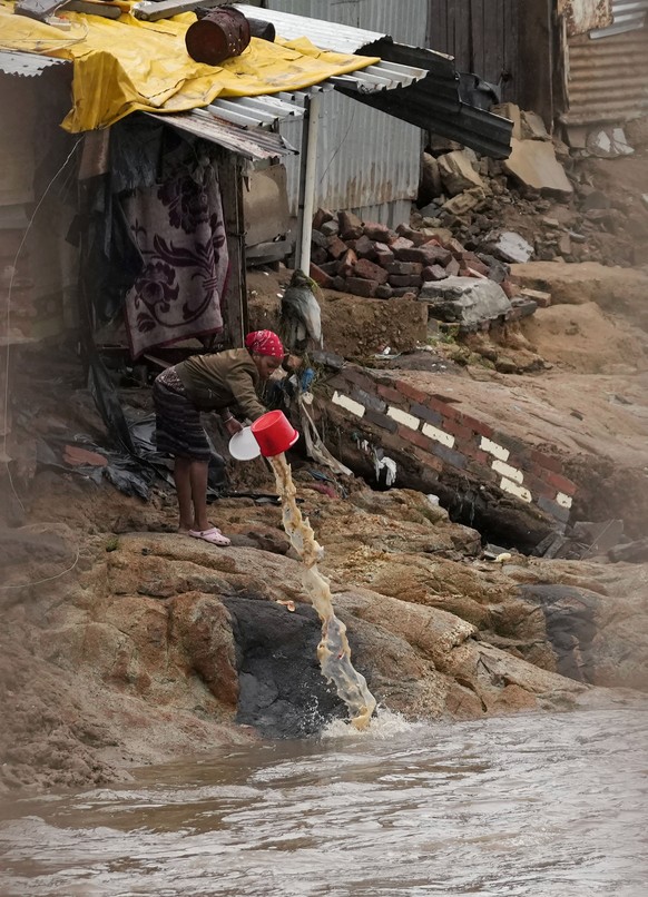 A woman clears water from a squatter camp on the edge of the Jukskei river by Alexandra township after heavy rain fall, in Johannesburg, South Africa, Monday, Feb. 13, 2023. (AP Photo/Themba Hadebe)