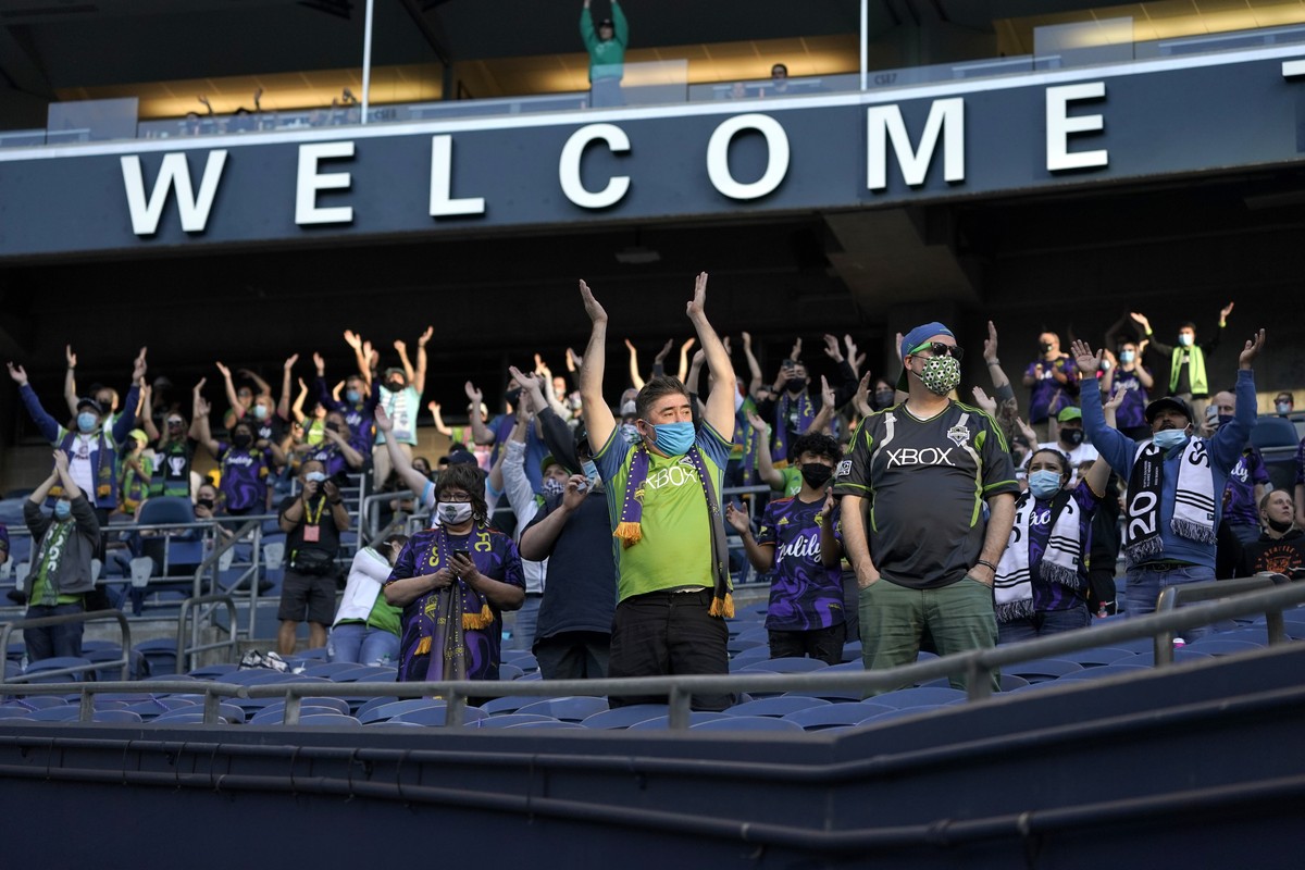 Fans sitting in socially distanced groups perform the "Boom Boom Clap" cheer at the start of an MLS soccer match between the Seattle Sounders and Minnesota United, Friday, April 16, 2021, in ...
