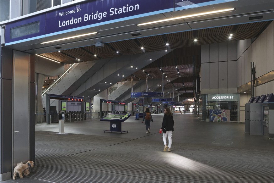 A woman walks her dog into an almost empty London Bridge station in London, Tuesday June 21, 2022. Britain&#039;s biggest rail strike in decades went ahead Tuesday after last-minute talks between a un ...