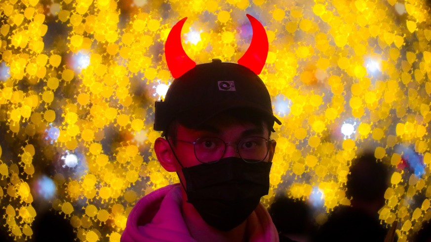 epa09653913 An image made by using a custom bokeh filter shows a person wearing a face mask walking past light decorations ahead of Christmas celebrations in Taipei, Taiwan, 22 December 2021. The Taiw ...