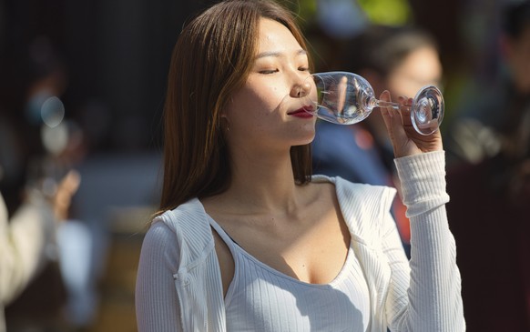 epa08782180 A woman tastes wine on the 9th East Helan Mountain Area International Wine Expo venue in Yinchuan, Ningxia autonomous region, China, 22 October 2020 (issued 29 October 2020). Nestled in th ...
