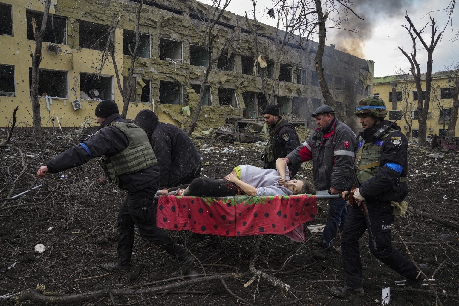 Ukrainian emergency workers and volunteers carry an injured pregnant woman from a maternity hospital damaged by an airstrike in Mariupol, Ukraine, on March 9, 2022. The image appears in a scene from t ...