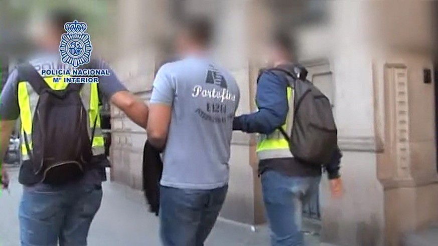 epa05902959 An undated handout photo made available by the Spanish National Police on 11 April 20117 shows two policemen escorting Russian programmer Pyotr Levashov (C) after his arrest in Barcelona,  ...