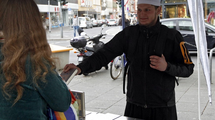 Ein Salafist uberreicht am Samstag (07.04.12) in Offenbach am Main waehrend einer Verteilaktion von kostenlosen Koranexemplaren einen Koran an eine Passantin. Die Aktion von Anhaengern des islamischen ...