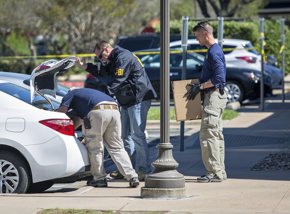 epa06616405 FBI agents are seen carrying items out in paper bags and boxes as they exit the FedEx store as the aid the police in investigate a fifth bombing this time at a FedEx location in Austin, Te ...