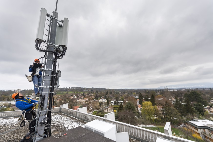 Deux employes de l&#039;entreprise Axians installent une antenne 5G de communication pour les mobiles sur un mat situe sur le toit d&#039;un immeuble du quartier de la Gradelle a Chene-Bougeries ce ve ...