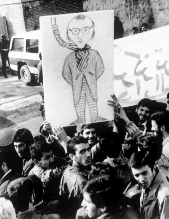Muslim students display a drawing of Salman Rushdie, writer of the book &quot;Satanic Verses&quot;, outside the former British Embassy in Tehran, Iran, Feb. 18, 1990. (AP Photo)
