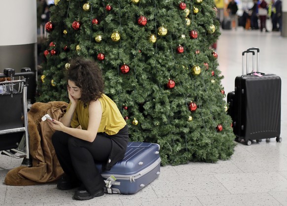 A woman waits in the departures area at Gatwick airport, near London, as the airport remains closed with incoming flights delayed or diverted to other airports, after drones were spotted over the airf ...