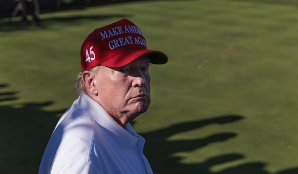 epa10799208 Former US President Donald J. Trump stands at the 16th tee box to watch the last groups in the third round play through at the LIV Golf tournament at Trump National Golf Club Bedminster in ...