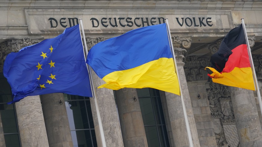 epa09830572 The national flag of the Ukraine (C) waves in front of the Reichstag building on the occasion of the video address of the Ukrainian President to the German parliament in Berlin, Germany, 1 ...