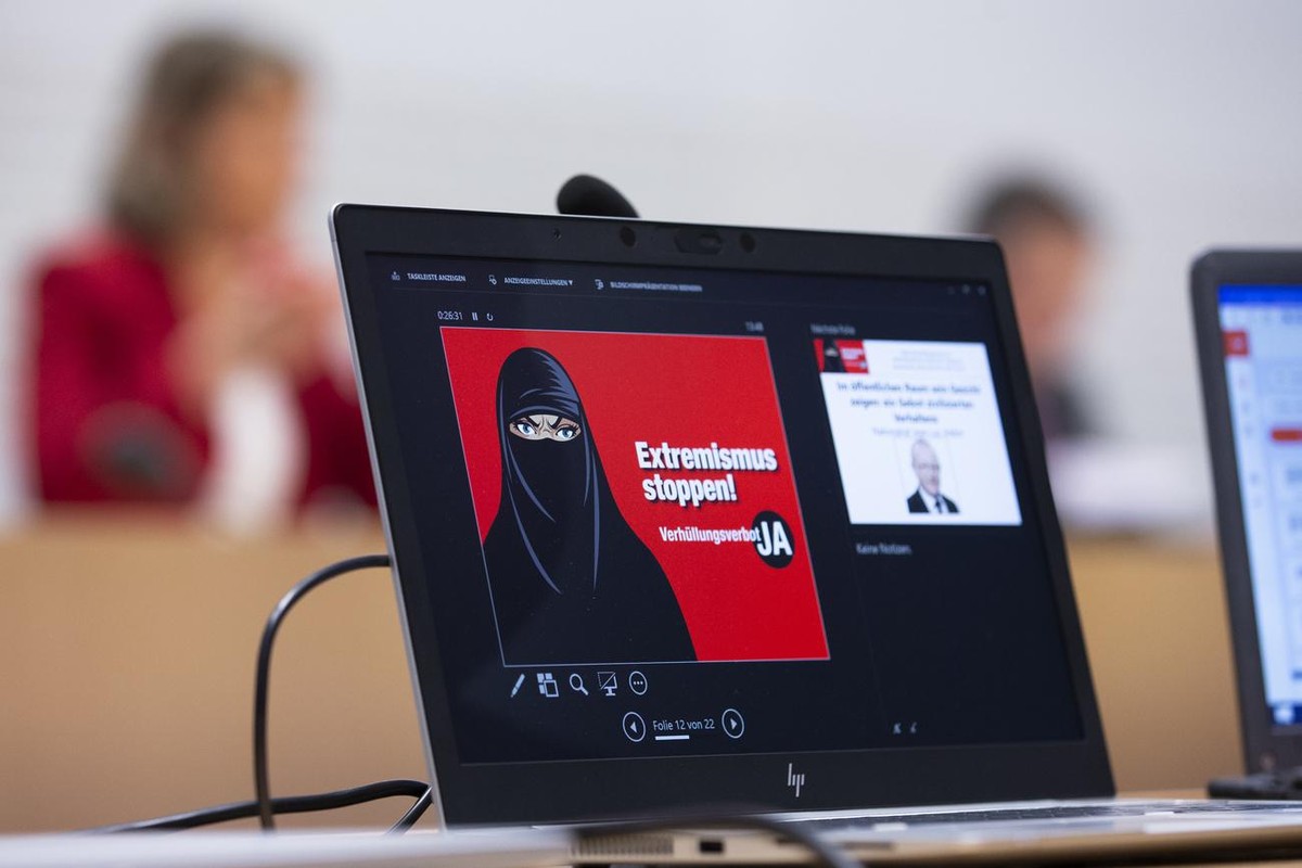 Das Abstimmungsplakat mit der Aufschrift "Extremismus stoppen! Verhuellungsverbot JA" wird auf einem Bildschirm angezeigt, waehrend einer Medienkonferenz zur Lancierung des Abstimmungskampfs ...