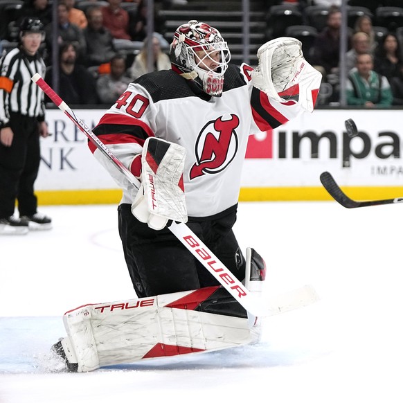 New Jersey Devils goaltender Akira Schmid, left, stops a shot as Anaheim Ducks center Sam Carrick watches during the third period of an NHL hockey game Friday, March 1, 2024, in Anaheim, Calif. (AP Ph ...