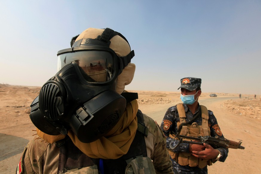 Iraqi forces wear protective masks after winds brought fumes from a nearby sulfur plant set alight by Islamic State militants, at south of Mosul in Qayyara, Iraq, October 22, 2016. REUTERS/Alaa Al-Mar ...