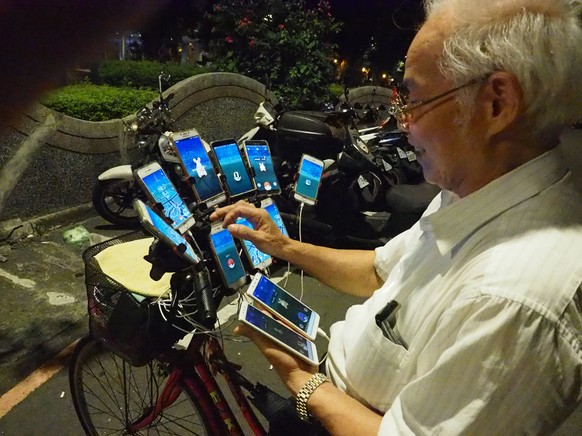 epa06936007 Chen San-yuan, a 69-year-old Feng Shui Master, used 11 cellphones to catch Pokemon in a park in New Taipei City, Taiwan, 08 August 2018. Chen was hooked on Pokemon Go in 2016 when his gran ...
