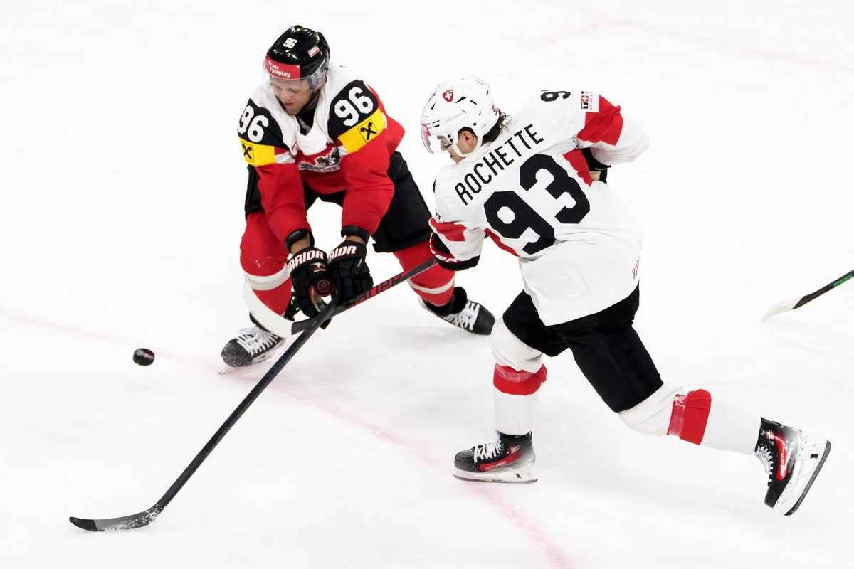 Switzerland's Theo Rochette, right, scores the seventh goal next to Austria's Mario Huber, left, during the 2026 IIHF Men's Ice Hockey World Championship preliminary round group A game  ...