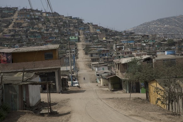 A woman walks on an empty street in Ventanilla, Lima, Peru, Wednesday, Aug. 12, 2020. Peruvian authorities and the Pan American Health Organization are investigating whether the country failed to coun ...