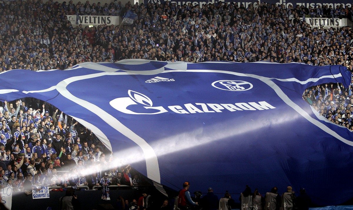 FILE - Soccer club FC Schalke 04 supporters unfold a giant team's jersey with the logo of Russian sponsor Gazprom, at the Veltins-Arena in Gelsenkirchen, Germany, on Jan. 20, 2007. The logo of Ru ...