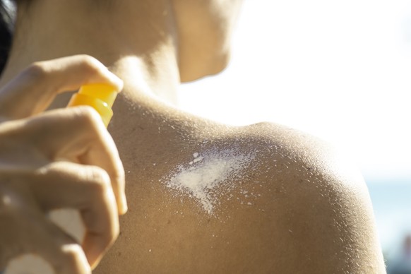 Mann wird eingecremt mit Sonnencreme-Spray