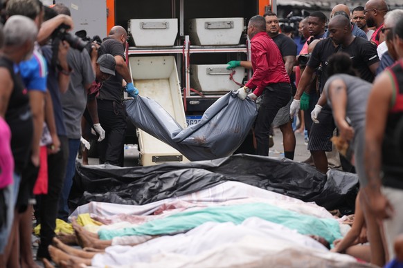 Forensic workers collect the bodies of people killed the day before during a police raid targeting the Comando Vermelho gang at the Complexo da Penha favela in Rio de Janeiro, Brazil, Wednesday, Oct.  ...