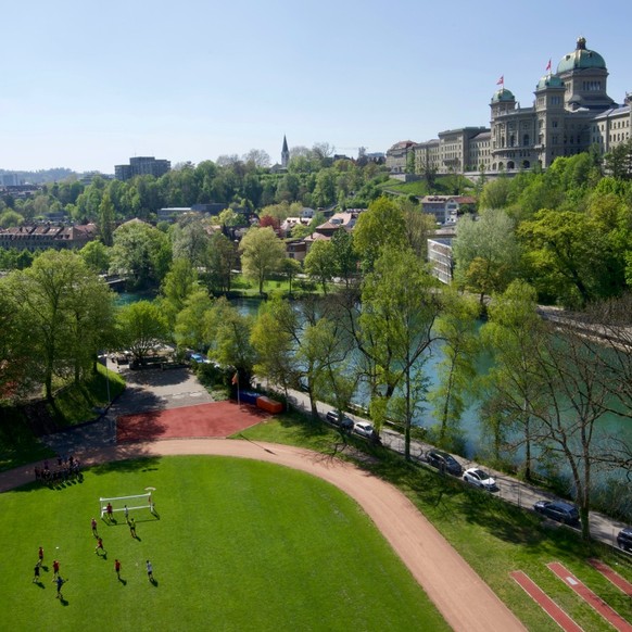 Birds eye view of footballers playing football on a football pitch with river and city background - Bern, Switzerland