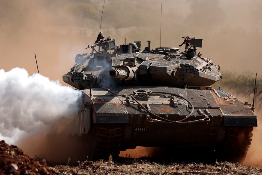 epa10935546 An Israeli Merkava tank in action during maneuvers at an undisclosed location along the border with Lebanon, in Israel, 24 October 2023. Tensions continue to rise at the border between Isr ...