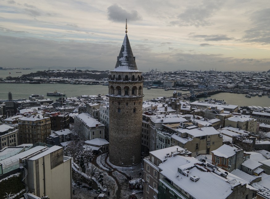 Snow covers streets and Galata tower after a heavy snowfall in Istanbul, Turkey, Tuesday, Jan. 25, 2022. Rescue crews in Istanbul and Athens on Tuesday cleared roads that had come to a standstill afte ...