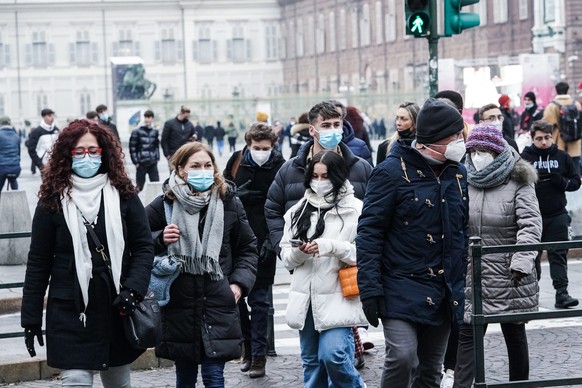epa09657910 People wearing protective face masks walk in the center of Turin, northern Italy, 27 December 2021. The Italian government on 24 December imposed a series of new COVID-19 prevention measures, including the obligation to wear facemasks outdoors, and reduced the duration of the 'Super Green Pass' health certificate, which is obligatory for all customers who eat food or have a drink inside a bar or restaurant.  EPA/TINO ROMANO