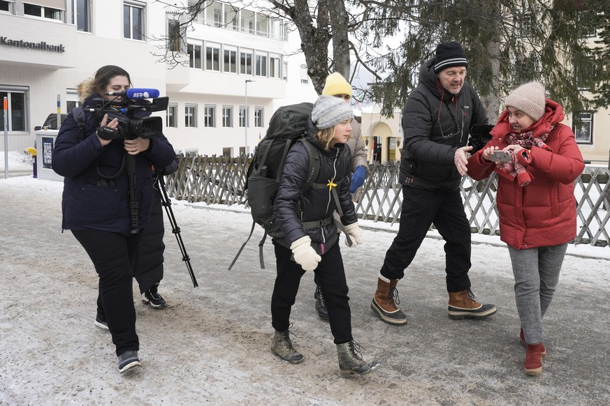 A woman is trying to take a photo with her mobile device from climate activist Greta Thunberg of Sweden, leaving with a backpack the World Economic Forum in Davos, Switzerland Friday, Jan. 20, 2023. T ...