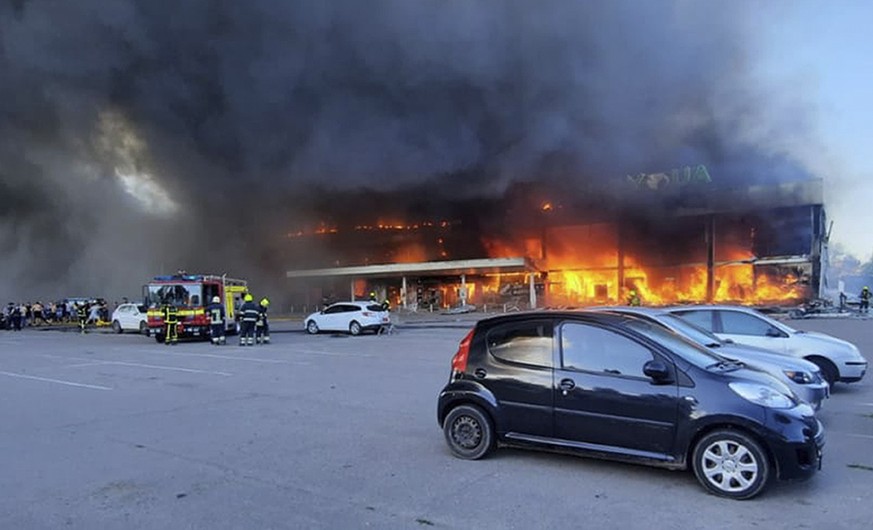 In this image made from video provided by Ukrainian State Emergency Service, firefighters work to extinguish a fire at a shopping center burned after a rocket attack in Kremenchuk, Ukraine, Monday, Ju ...