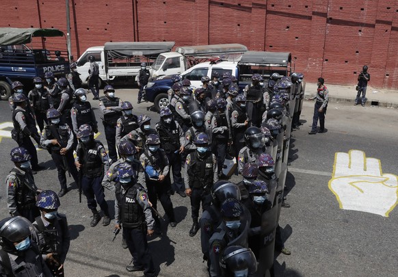 epaselect epa09035085 Anti-riot police officers deploy next to a graffiti of three-finger salute after a clash between pro-junta supporters and anti-coup protesters in Yangon, Myanmar, 25 February 202 ...