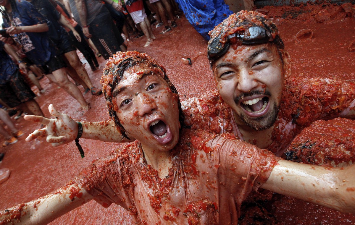 epa06171503 People covered in squashed tomatoes take part in the traditional tomato fight called 'Tomatina' in Bunol, Spain, 30 August 2017. As every year on the last Wednesday of August, th ...