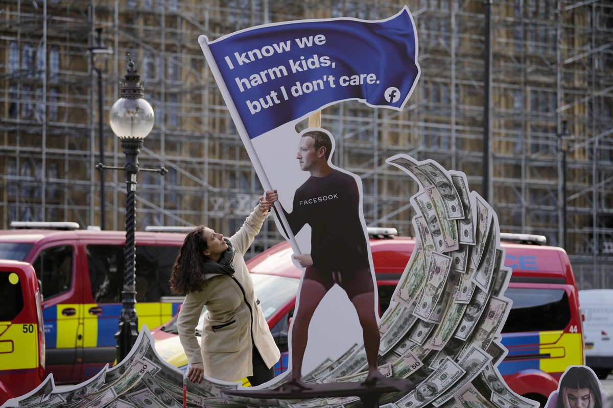 Senior campaigner Flora Rebello Arduini adjusts an installation outside parliament in Westminster in London, Monday, Oct. 25, 2021. A 4-metre-high installation depicting Mark Zuckerberg surfing on a w ...