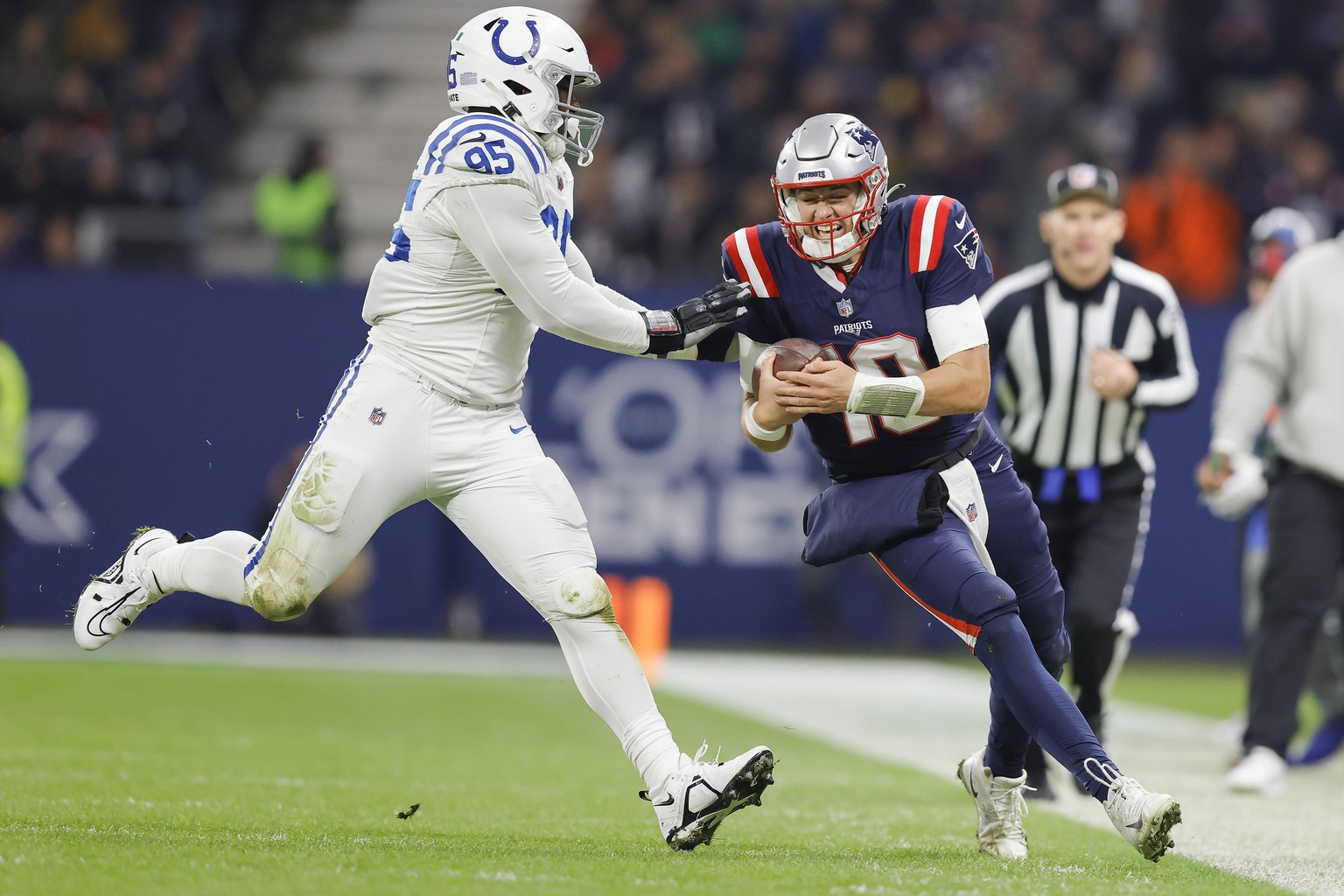 epa10972005 New England Patriots quarterback Mac Jones (R) is pushed out of bounds by Indianapolis Colts defensive end Adetomiwa Adebawore (L) during the second half of the NFL game between the Indian ...