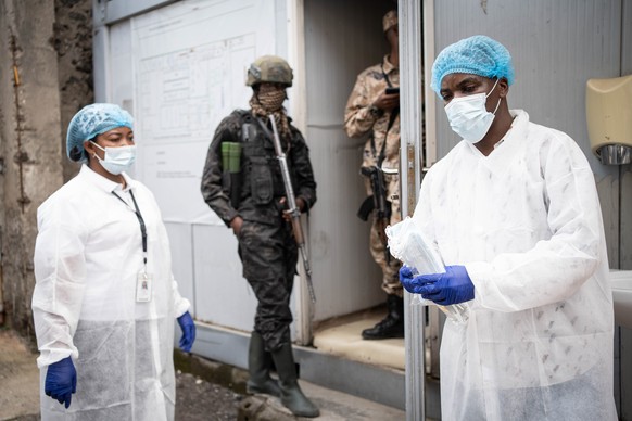 epa12973891 A staff in protective gown distributes facemaskes as a preventive measure against Ebola at the National Institute of Biomedical Resesarch (NIRB) in Goma, North Kivu, Democratic Republic of ...