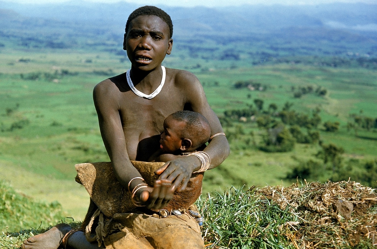 Eine Batwa-Mutter im Fellkleid bettelt um eine kleine Gabe bei Kisoro, Uganda, Zentralafrika, 1954.