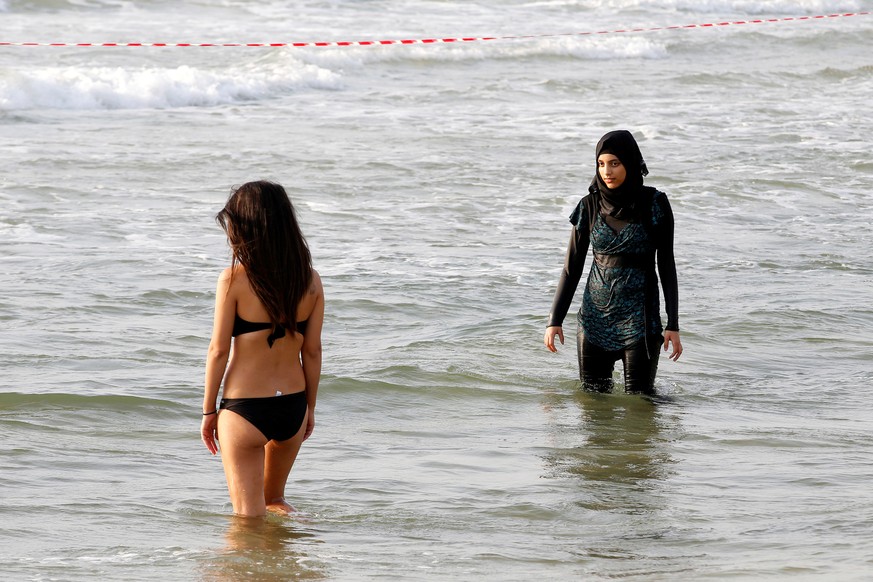 A Muslim woman wearing a Hijab stands next to a woman wearing a bikini in the Mediterranean Sea at a beach in Tel Aviv, Israel August 30, 2016. Picture taken August 30, 2016. REUTERS/Baz Ratner